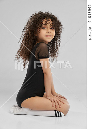 Girl in leotard sitting on studio floor. Girl in leotard sitting on studio floor. 64013946