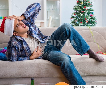 Man having hangover after christmas party 64015894