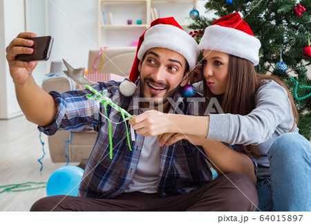Young pair taking selfies during christmas 64015897