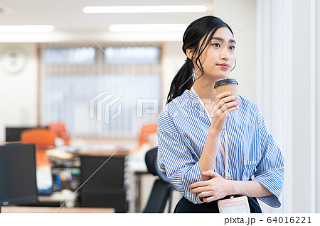 オフィスで飲み物を飲む若い女性社員の写真素材
