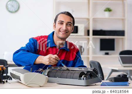 Young repairman repairing air-conditioner at warranty center 64018564