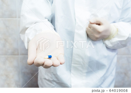 Blue and white pill in doctors hand Blue and white pill in doctors hand 64019008