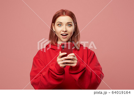 Happy ginger woman with phone in her hands standing in studio 64019164