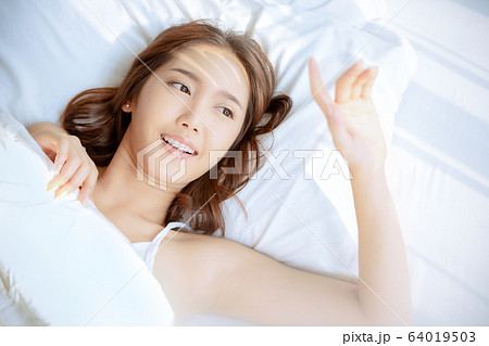 女性 綺麗 美人 起床 ベッド 寝室 日差し 朝の写真素材