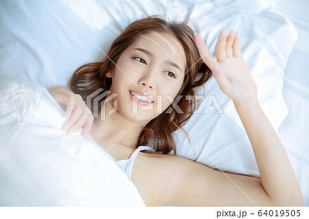 女性 綺麗 美人 起床 ベッド 寝室 日差し 朝の写真素材