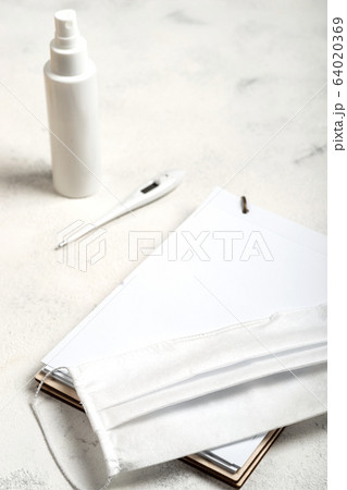 Notebook with place for text and surgical mask, hand sanitizer and digital thermometer on the white background. close-up. 64020369