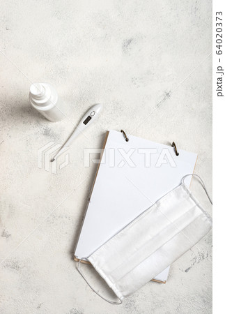 Notebook with place for text and surgical mask, hand sanitizer and digital thermometer on the white background. Concept of the fight against coronovirus, covid -19. Flat lay. 64020373