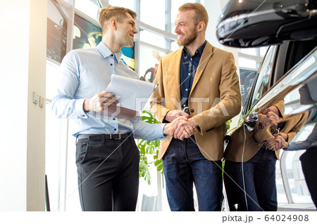 affable handsome consultant and client in dealership 64024908
