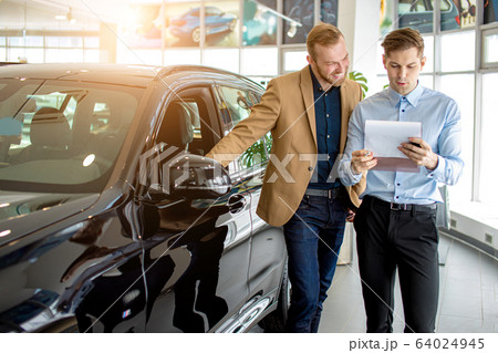 young consultant talking about features of new car 64024945