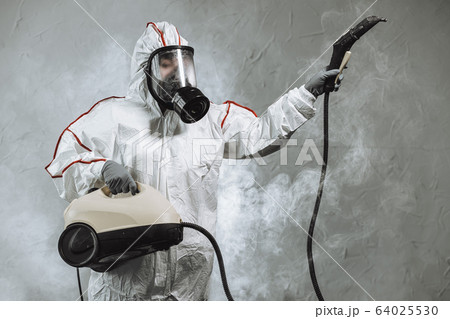 disinfector in protective suit conducts disinfection 64025530