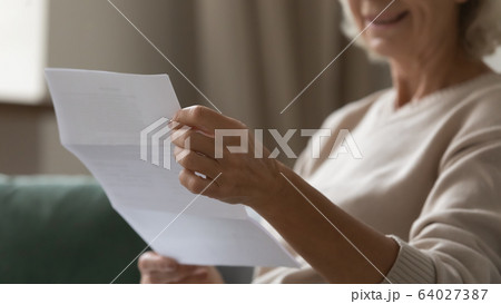 Close up wrinkled female hands holding paper document. Close up wrinkled female hands holding paper document. 64027387