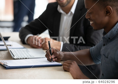 Close up happy african american businessman signing partnership agreement. 64028296