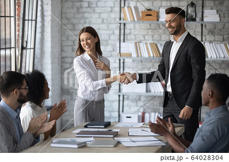 Smiling businessman shaking hand and congratulations young attractive businesswoman. 64028304