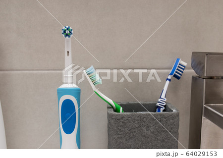 An electric toothbrush and an old toothbrush near the washbasin. An electric toothbrush and an old toothbrush near the washbasin. 64029153