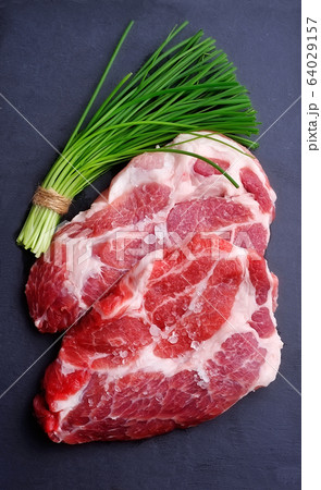 Crude meat with green onion on black board. 64029157