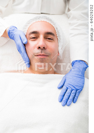 Portrait of smiling man lying in beauty salon 64029202