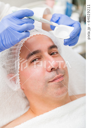 Man lies on spa and has transparent facial mask 64029211