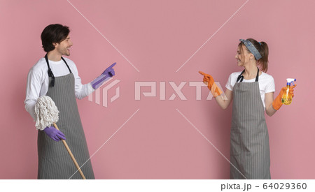 Happy Couple With Cleaning Instruments In Hands Pointing At Copy Space Happy Couple With Cleaning Instruments In Hands Pointing At Copy Space 64029360