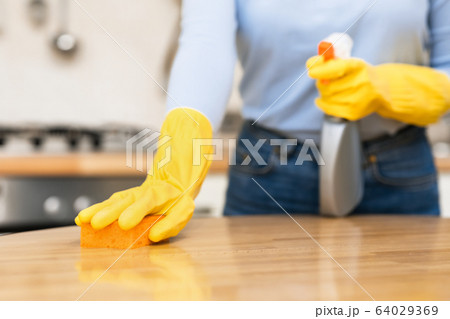 Young woman cleaning kitchen table using spray and sponge Young woman cleaning kitchen table using spray and sponge 64029369