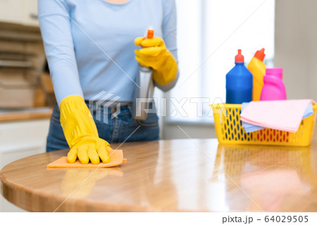 Young woman cleaning kitchen table using spray and rag Young woman cleaning kitchen table using spray and rag 64029505