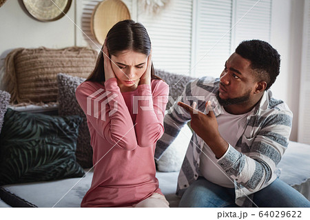 Husband scolds wife. Woman covers her ears 64029622