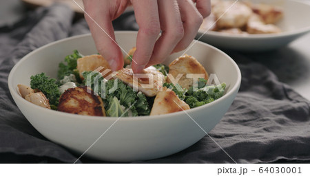 man hands making caesar salad with kale and turkey in white bowl, add turkey 64030001