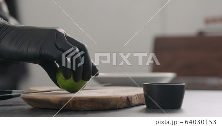 man hands in black gloves take lime on olive wood board 64030153