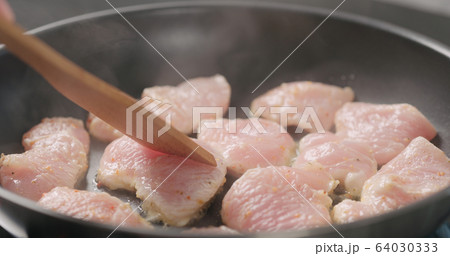 shot of frying turkey fillet pieces on nonstick pan and moving them with wood spatula shot of frying turkey fillet pieces on nonstick pan and moving them with wood spatula 64030333