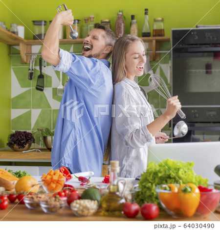 Young unrecognizable couple preparing healthy lunch and funny singing 64030490