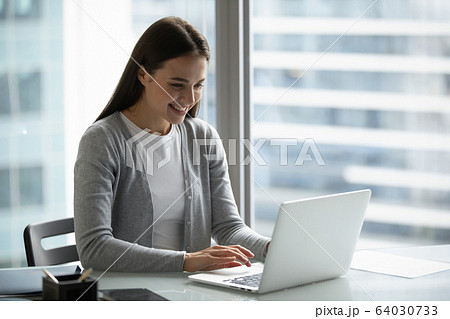 Smiling female work on laptop in modern office Smiling female work on laptop in modern office 64030733