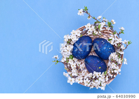 Blue easter eggs in a basket with flowers on a Blue easter eggs in a basket with flowers on a 64030990