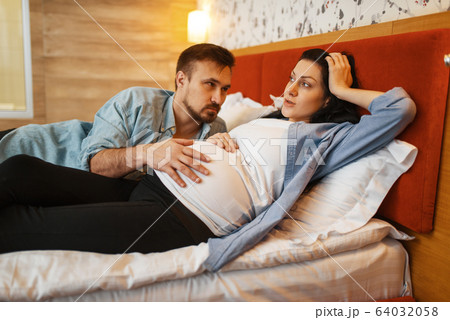 Husband listens to baby in pregnant wife's stomach 64032058