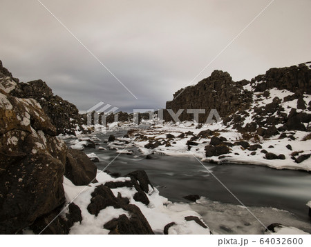 A small river between snow-covered rocks 64032600