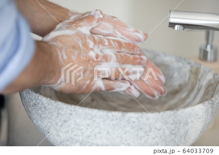 Young responsible caucasian man cleaning hands with antibacterial soap. 64033709