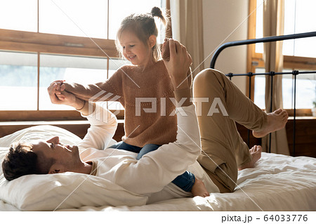 Happy young father having fun with daughter in bedroom. Happy young father having fun with daughter in bedroom. 64033776