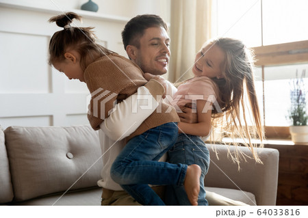 Excited young father holding two playful kids siblings. 64033816