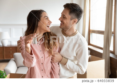 Happy homeowners cuddling, amazed by real estate purchase. 64033839