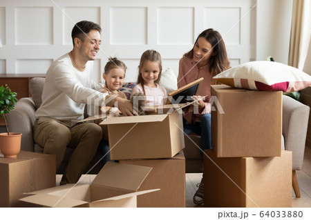 Happy couple unboxing family belongings with daughters. Happy couple unboxing family belongings with daughters. 64033880