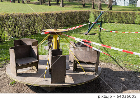 Corona virus COVID-19 restriction. No people due to quarantine. Closed urban park. Empty park and playground. Stay at home compaign. Red warning tape on ramps and slides. Social distancing 64036005