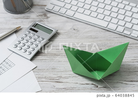 Top view office workspace with green paper ship 64038845