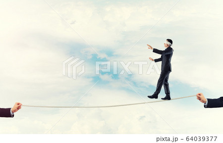 Business concept of risk support and assistance with man balancing on rope 64039377