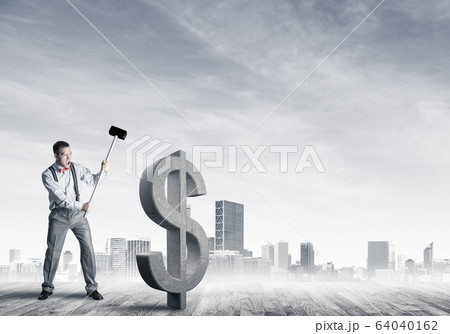 Determined banker man against modern cityscape breaking dollar c Determined banker man against modern cityscape breaking dollar c 64040162