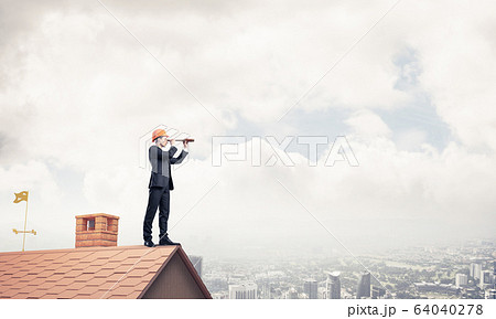 Engineer man standing on roof and looking in spyglass. Mixed med Engineer man standing on roof and looking in spyglass. Mixed med 64040278