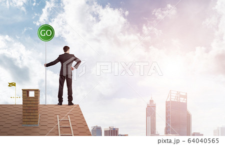 Businessman in suit on house top with ecology concept signboard. Mixed media 64040565