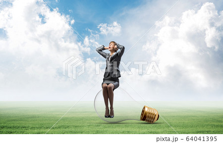 Stressful woman sitting on big light bulb Stressful woman sitting on big light bulb 64041395