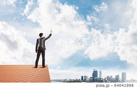 Businessman on house roof touch empty space. Mixed media 64041998
