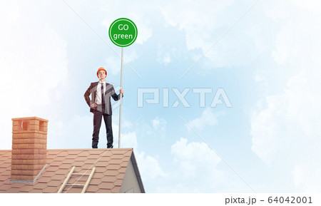 Businessman in suit on house top with ecology concept signboard. 64042001
