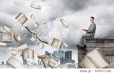 Man on roof reading book and many of them flying in air Man on roof reading book and many of them flying in air 64042186