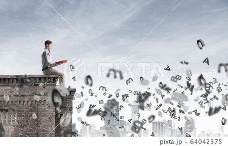 Man on roof edge reading book and symbols flying around Man on roof edge reading book and symbols flying around 64042375