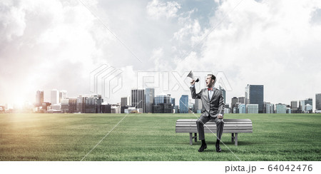 Businessman in summer park announcing something in loudspeaker a 64042476